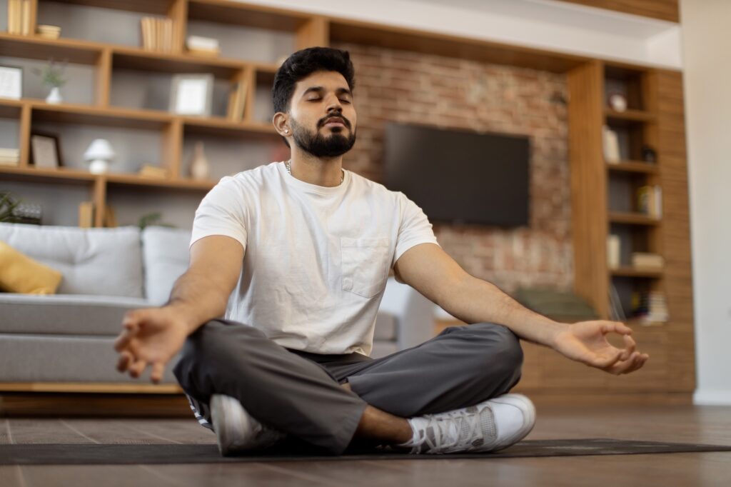 Arabian man with closed eyes meditating on yoga mat