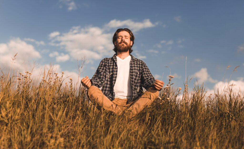 Bearded man meditating in field