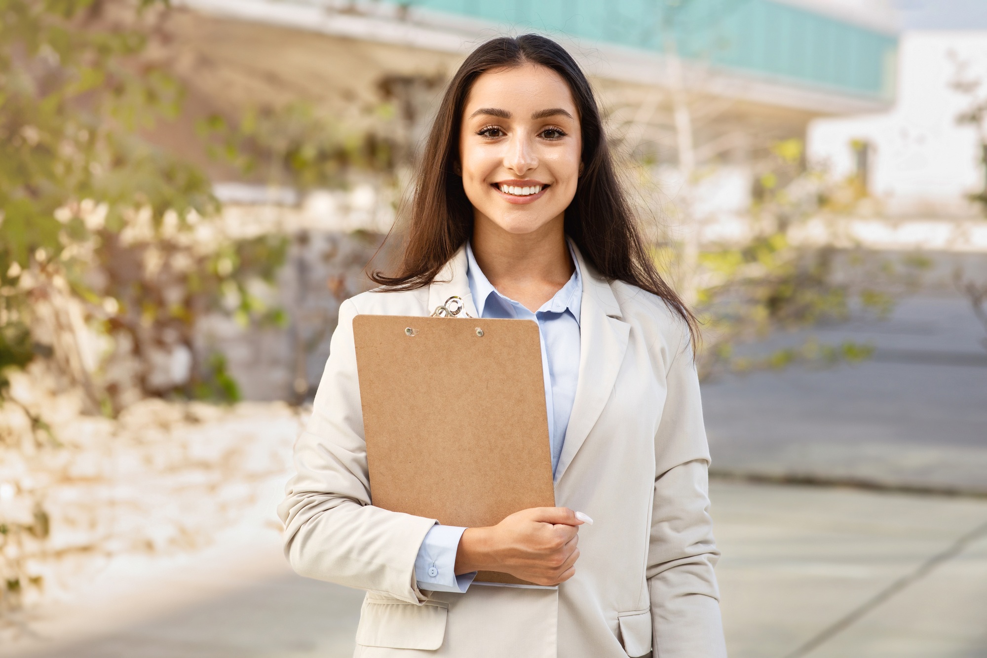 Happy pretty confident millennial woman manager in suit with clipboard enjoy work