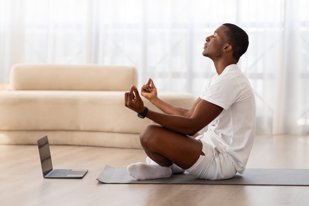 Man meditating at home on yoga mat